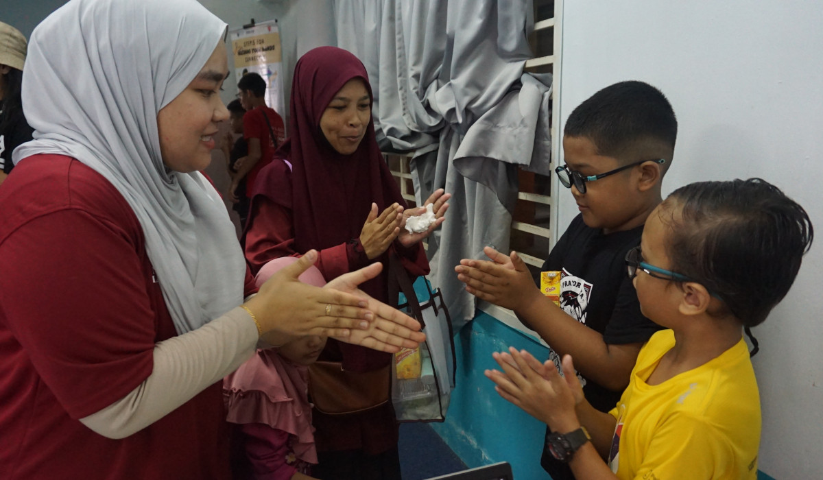 Sukarelawan mengajar kaedah mencuci tangan yang betul kepada kanak-kanak