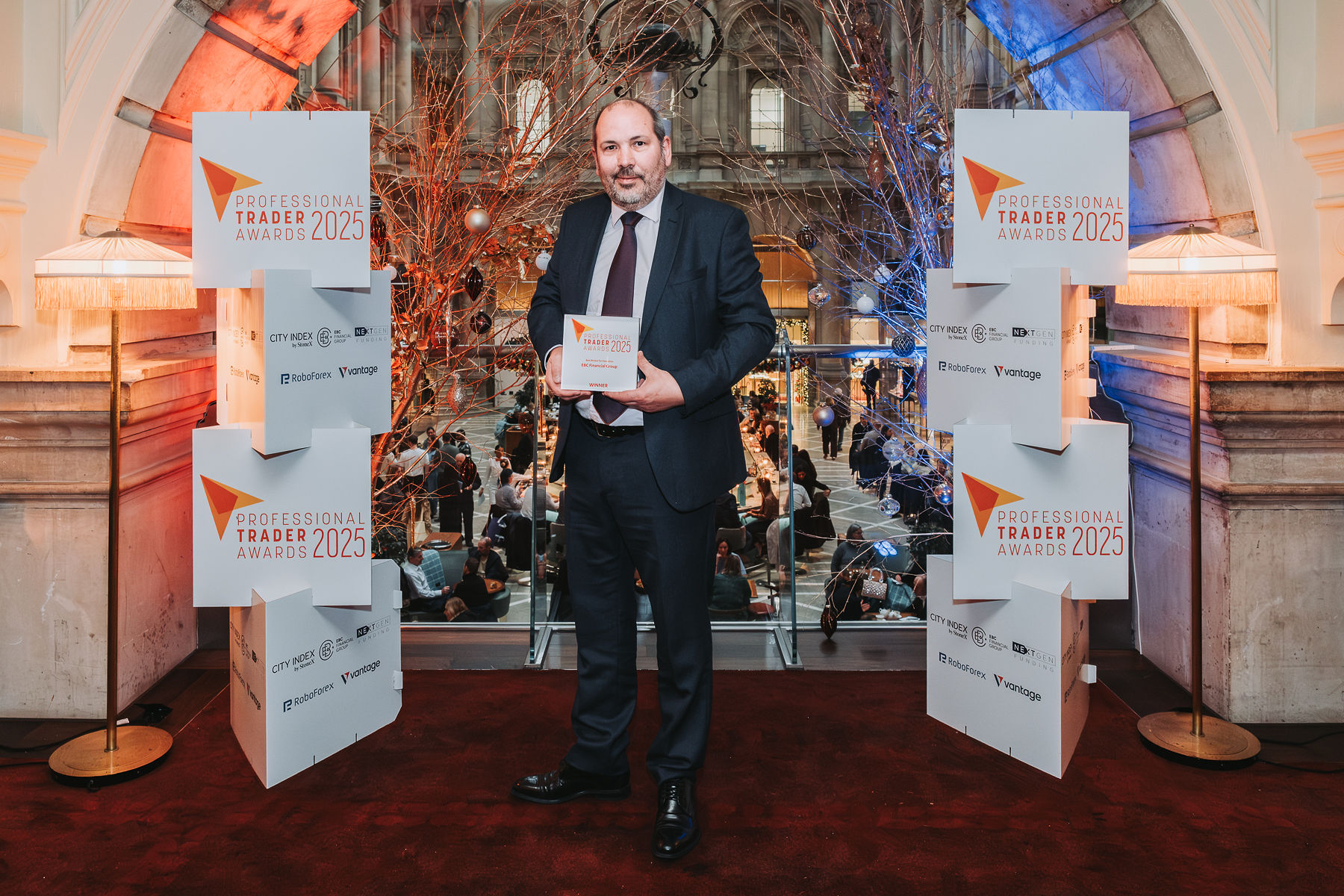 Christopher Potts standing on stage receiving the Best Broker for Execution trophy at the Professional Trader Awards 2025, organised by Holiston Media