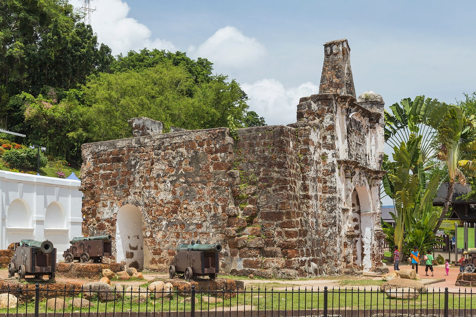 The stone gateway ruins of A Famosa fortress in Melaka, with old cannons in front